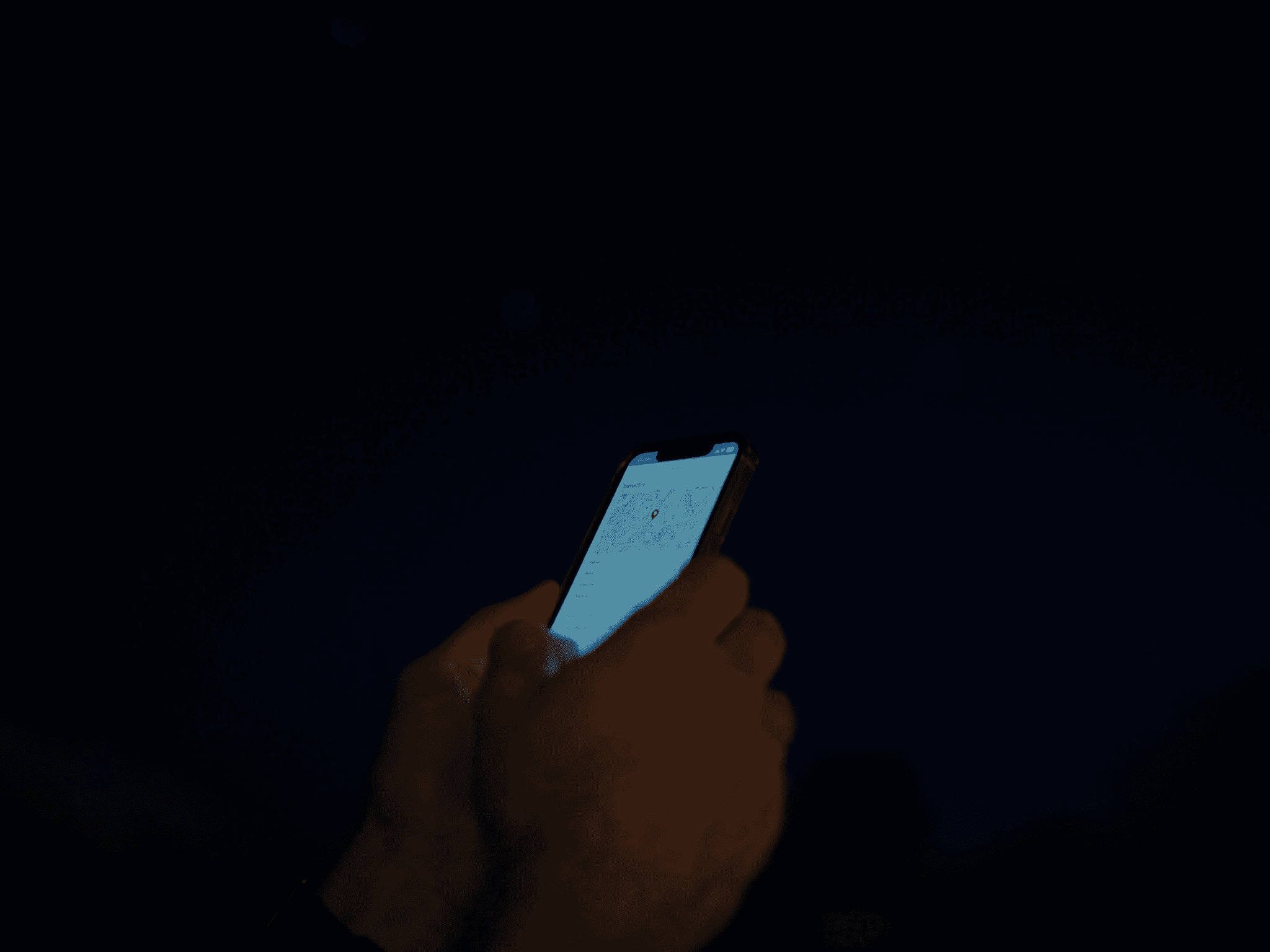 Hands holding a smartphone open to a notes app outdoors at night