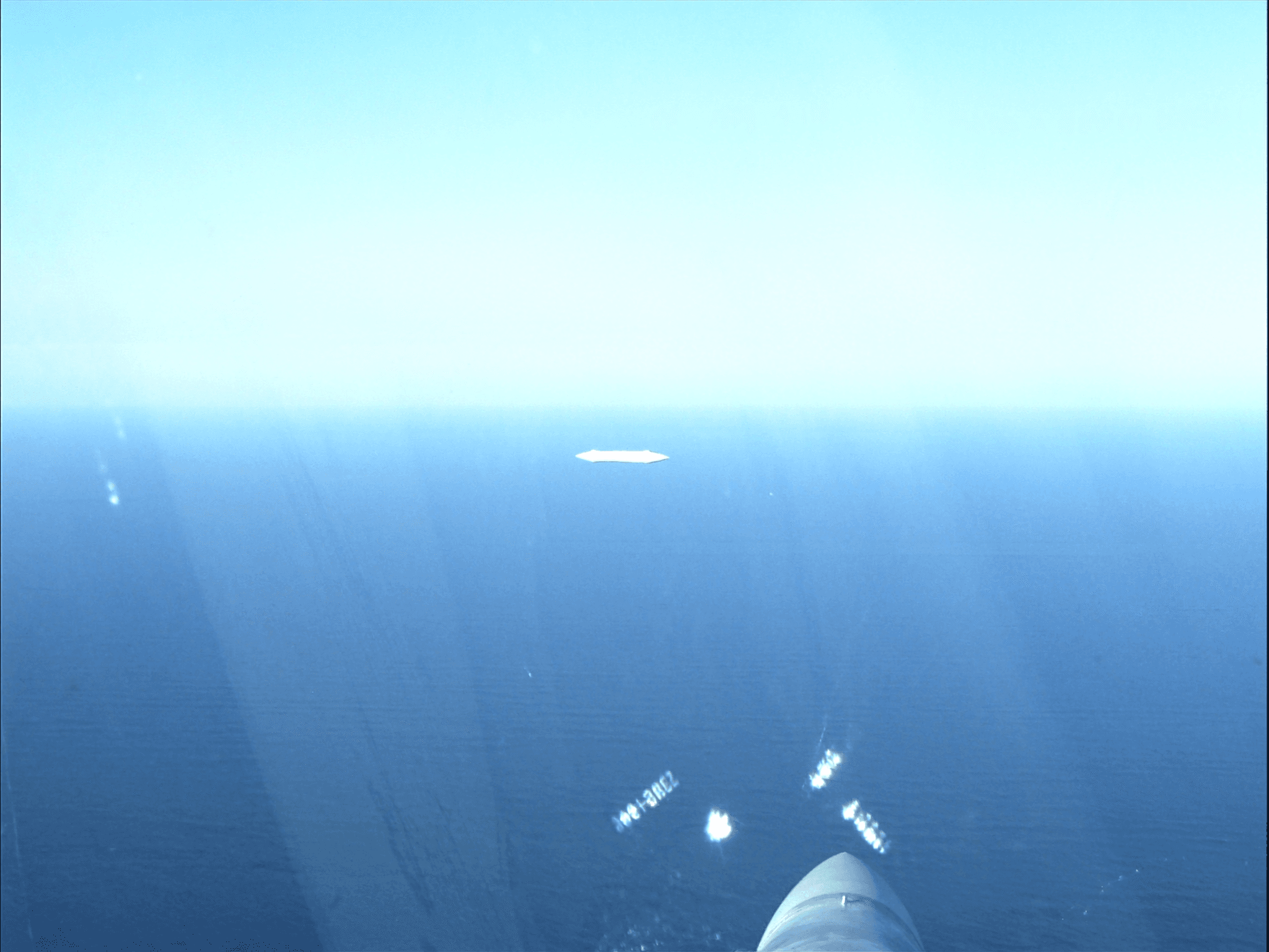 F/A-18 cockpit view over the Pacific Ocean with a distant white oblong object
